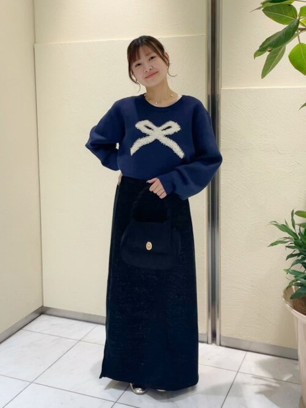 ブルー系のニット/セーター、ブラック系のスカート、ブラック系のショルダーバッグを着用したレディースの冬コーディネートの1枚目の写真