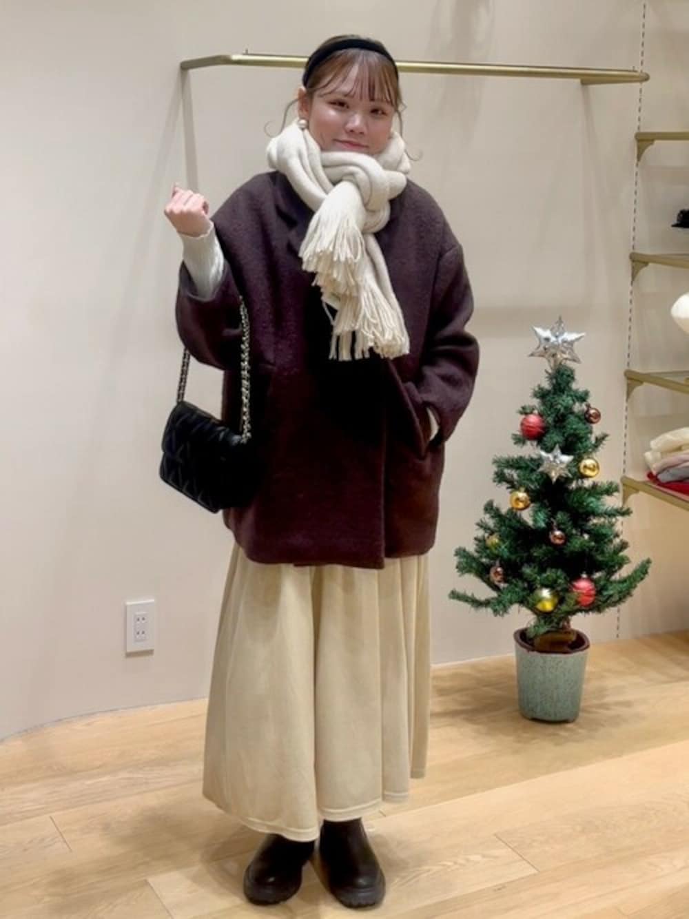 ブラウン系のチェスターコート、ブラック系のショルダーバッグ、ホワイト系のワンピースを着用したレディースの冬コーディネートの1枚目の写真