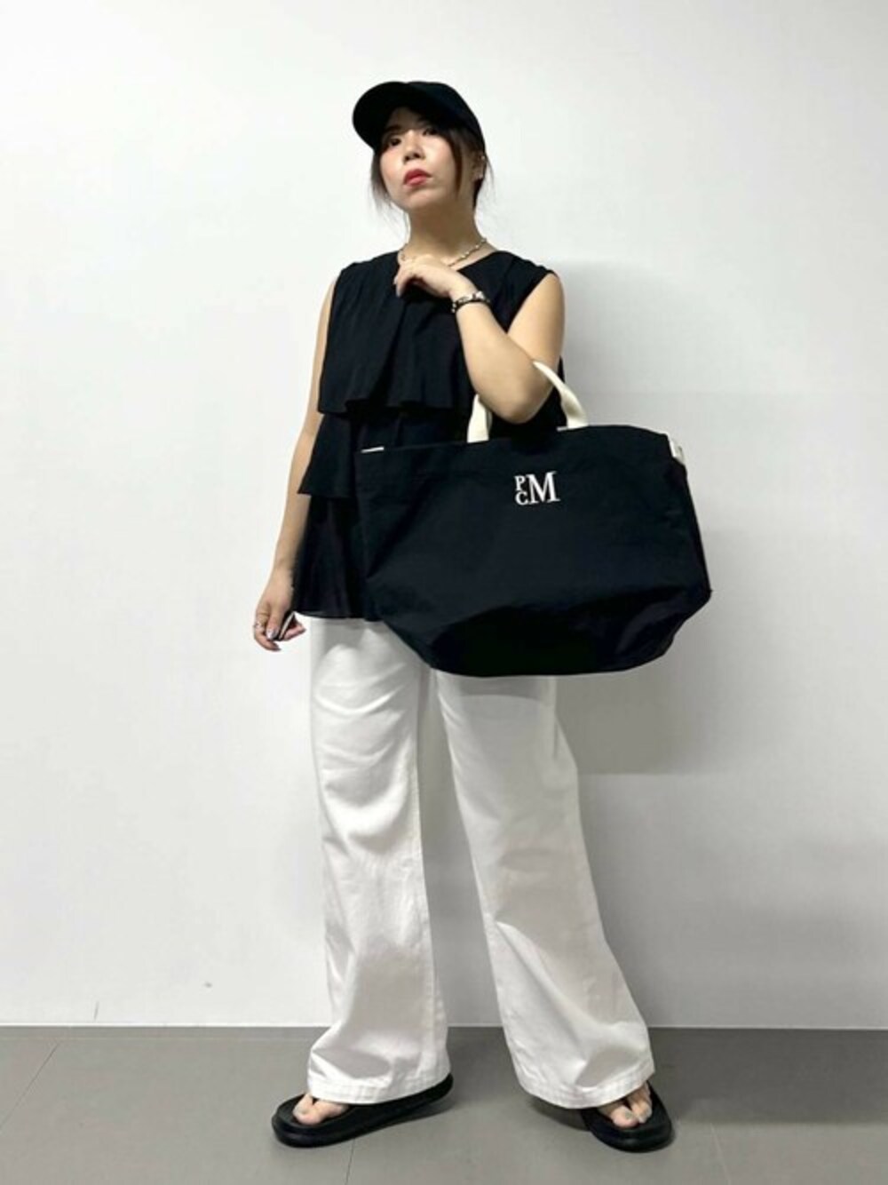 ブラック系のシャツ/ブラウス、ブラック系のトートバッグ、ブラック系のサンダルを着用したレディースの春コーディネートの1枚目の写真