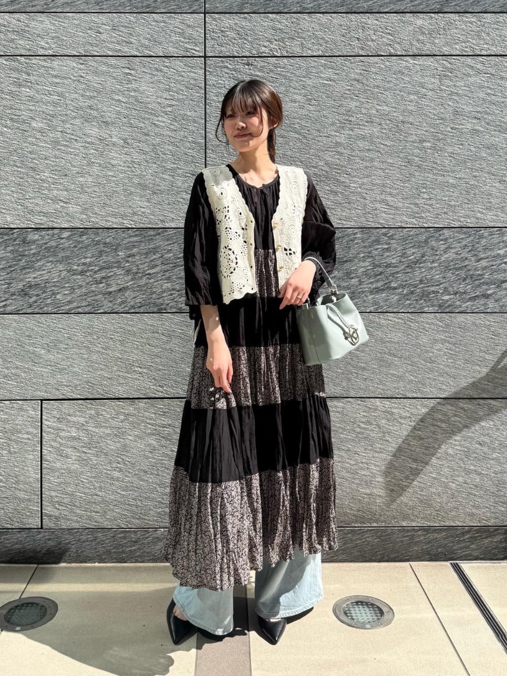 ブルー系のデニムパンツ、グリーン系のショルダーバッグ、ホワイト系のベストを着用したレディースの春コーディネートの1枚目の写真