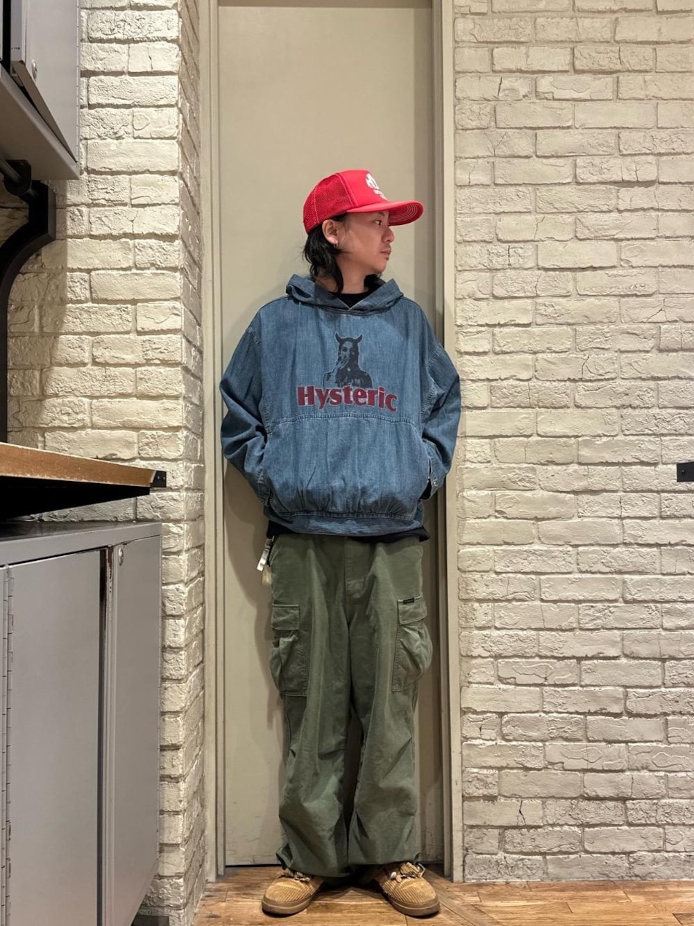 グリーン系のカーゴパンツ、レッド系のキャップを着用したメンズの秋コーディネートの1枚目の写真