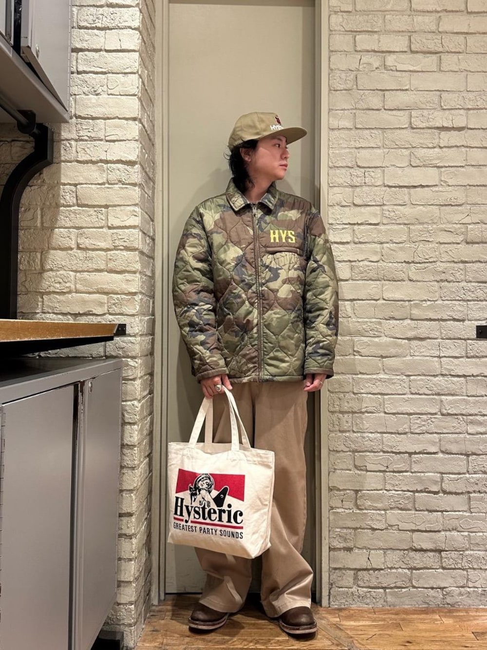 ベージュ系のその他パンツ、レッド系のトートバッグ、ベージュ系のキャップを着用したメンズの秋コーディネートの1枚目の写真