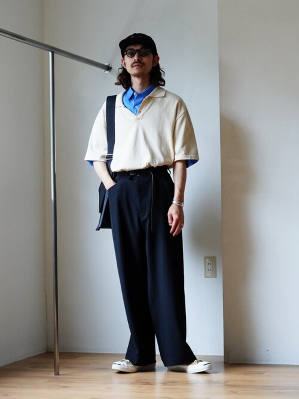 ベージュ系のポロシャツ、ブラック系のキャップを着用したメンズの春コーディネートの1枚目の写真