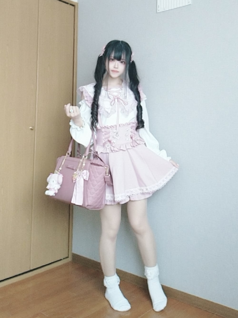 ピンク系のスカート、ホワイト系のシャツ/ブラウス、ピンク系のハンドバッグを着用したレディースの秋コーディネートの1枚目の写真