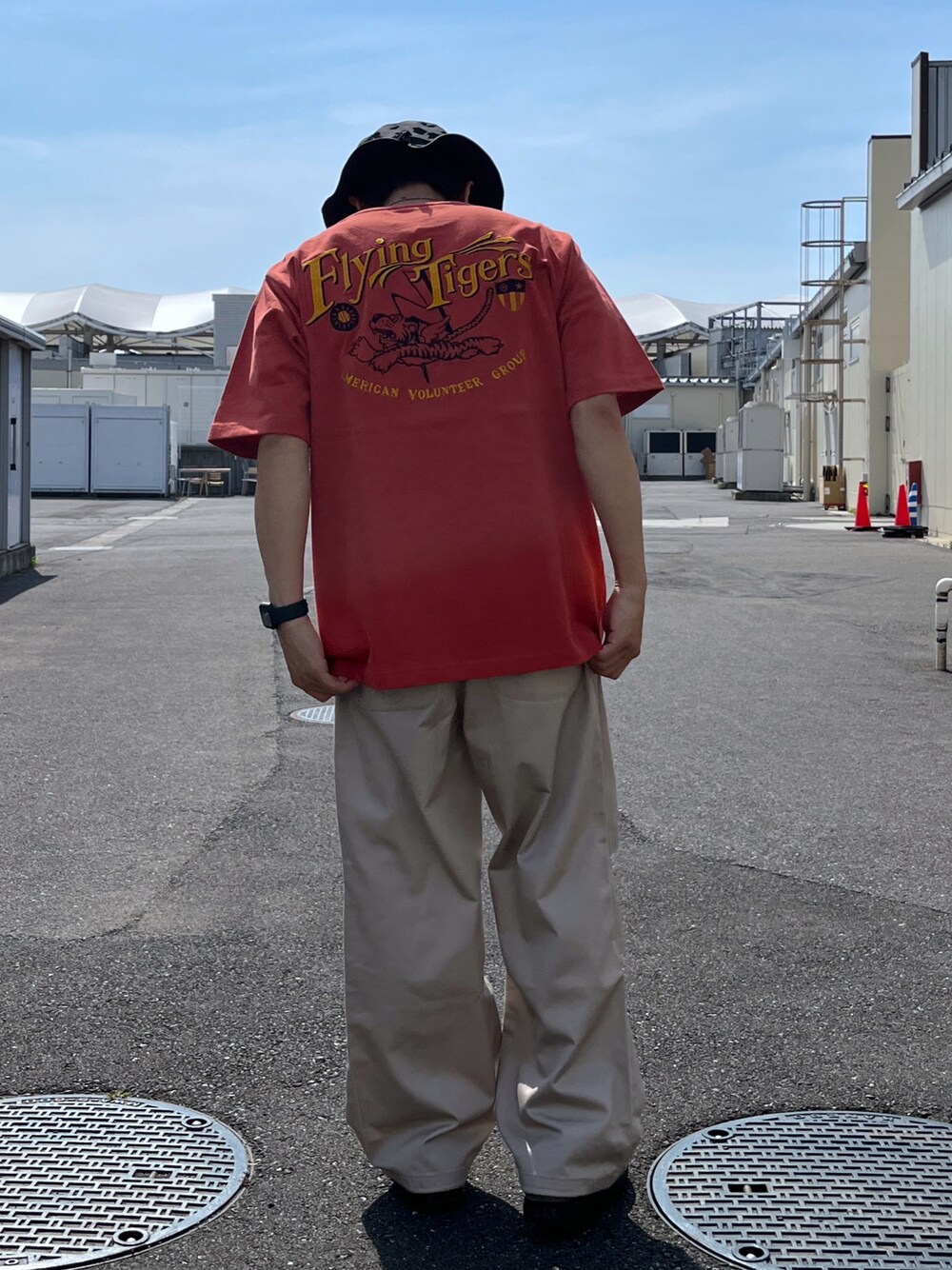 レッド系のTシャツ/カットソー、ベージュ系のパンツ、グリーン系のスニーカーを着用したメンズの春コーディネートの1枚目の写真