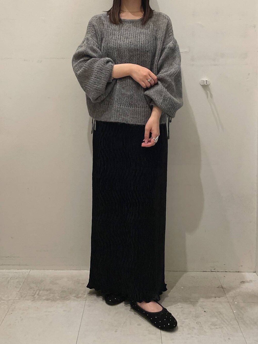 ブラック系のスカート、ブラック系のバレエシューズ、グレー系のニット/セーターを着用したレディースの秋コーディネートの1枚目の写真