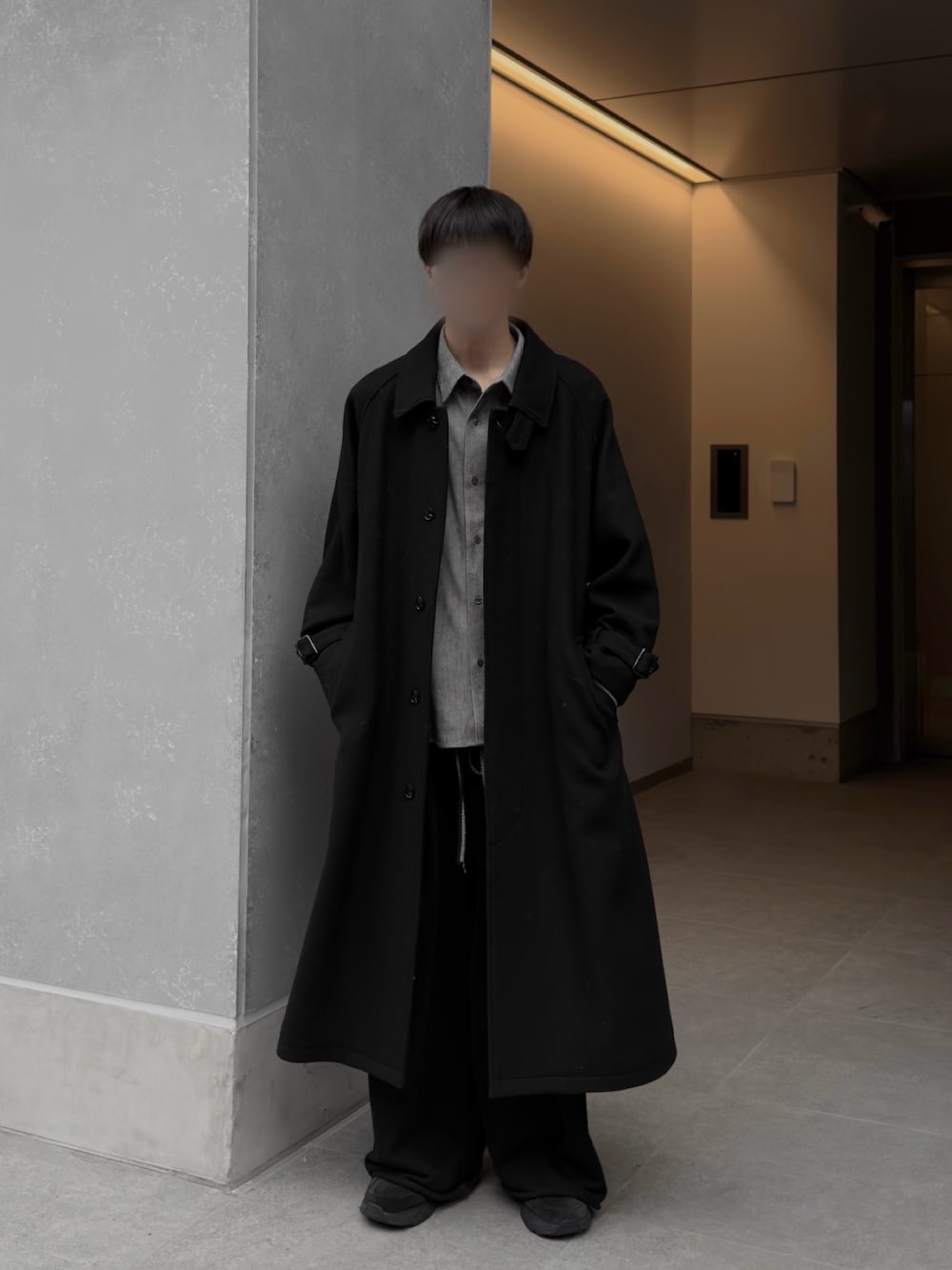 ブラック系のステンカラーコートを着用したメンズの秋コーディネートの1枚目の写真
