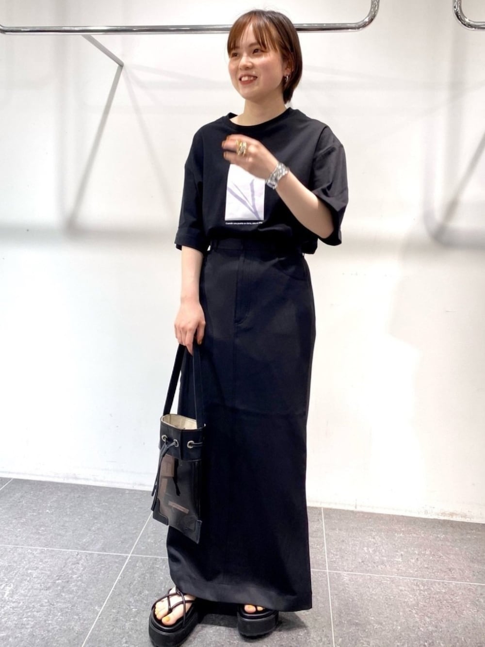 ブラック系のスカート、ブラック系のTシャツ/カットソー、ブラック系のサンダルを着用したレディースの春コーディネートの1枚目の写真