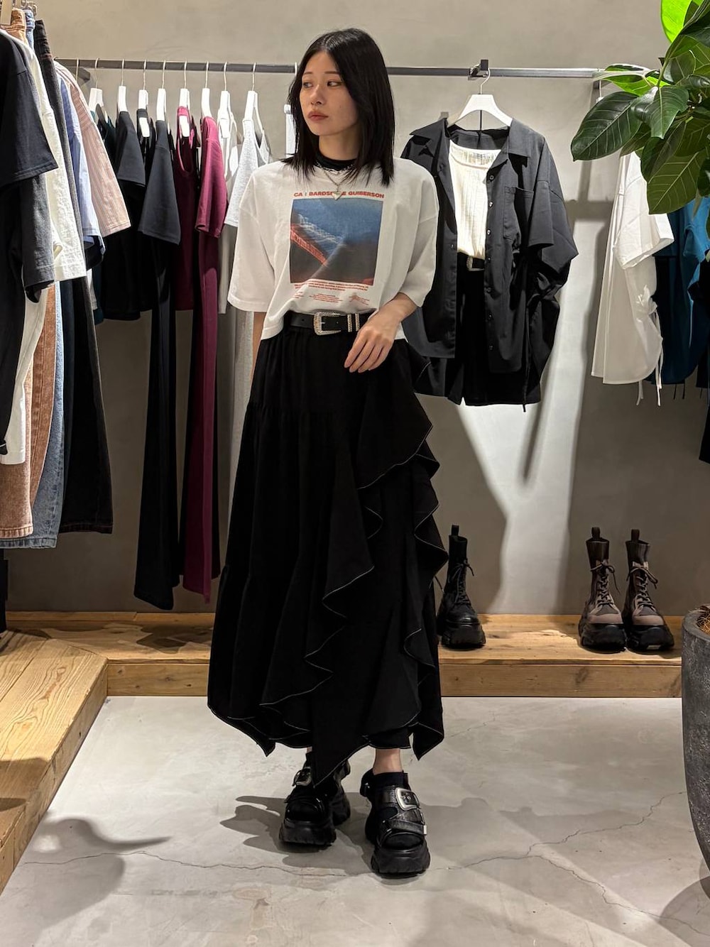 ブラック系のスカート、ブラック系のサンダル、ホワイト系のTシャツ/カットソーを着用したレディースの春コーディネートの1枚目の写真