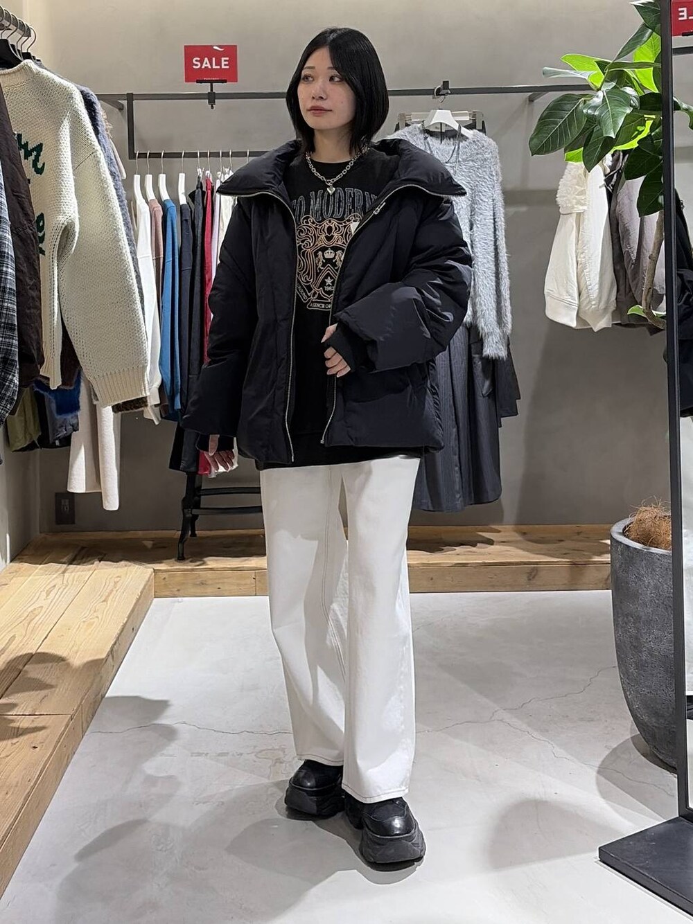 ブラック系のブーツ、ブラック系のブルゾン、ホワイト系のスラックスを着用したレディースの冬コーディネートの1枚目の写真