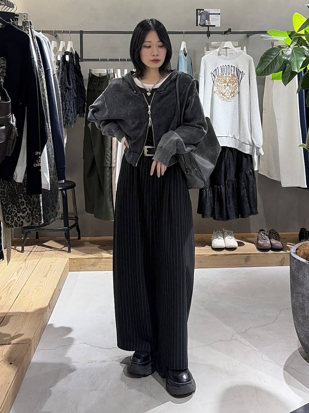 ブラック系のボストンバッグ、ブラック系のスラックス、グレー系のパーカーを着用したレディースの冬コーディネートの1枚目の写真