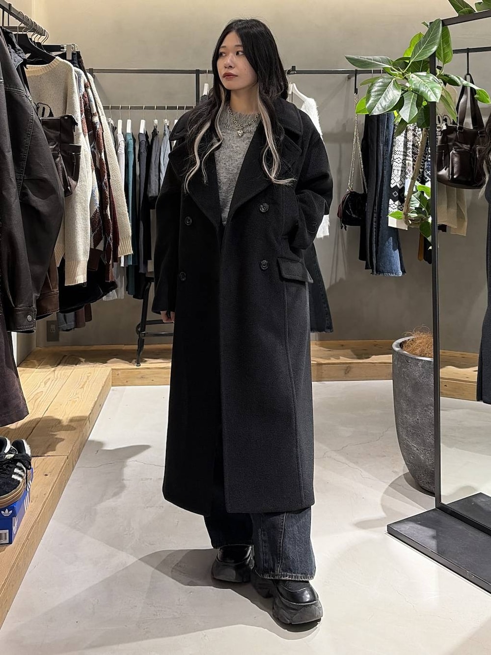 ブラック系のブーツ、ブルー系のデニムパンツ、ブラック系のチェスターコートを着用したレディースの冬コーディネートの1枚目の写真