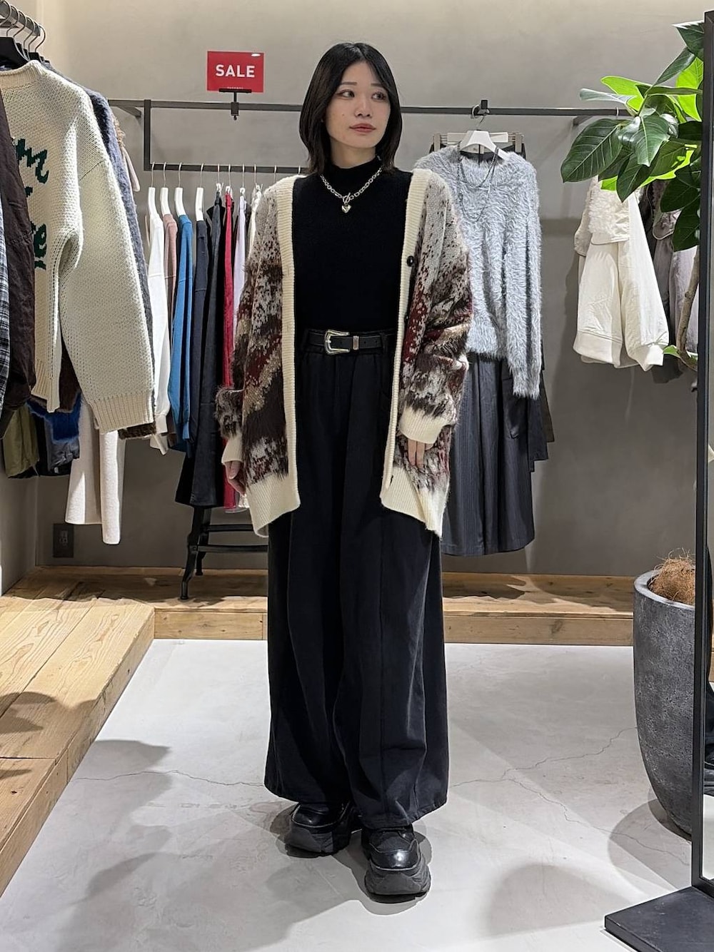 ブラック系のブーツ、ホワイト系のカーディガン/ボレロ、ブラック系のニット/セーターを着用したレディースの冬コーディネートの1枚目の写真