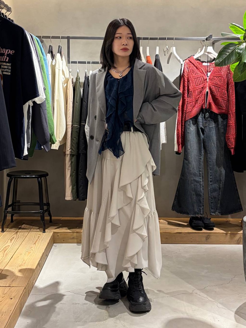 ブラック系のブーツ、ベージュ系のスカート、グレー系のテーラードジャケットを着用したレディースの春コーディネートの1枚目の写真