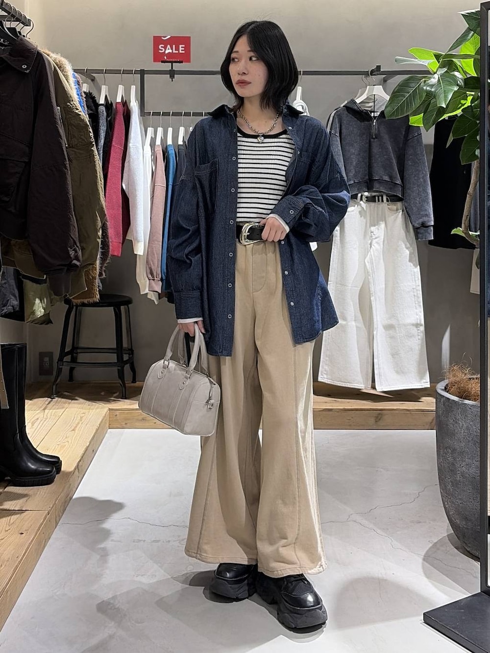 ブラック系のブーツ、ホワイト系のボストンバッグ、ブラウン系のスウェットパンツを着用したレディースの冬コーディネートの1枚目の写真