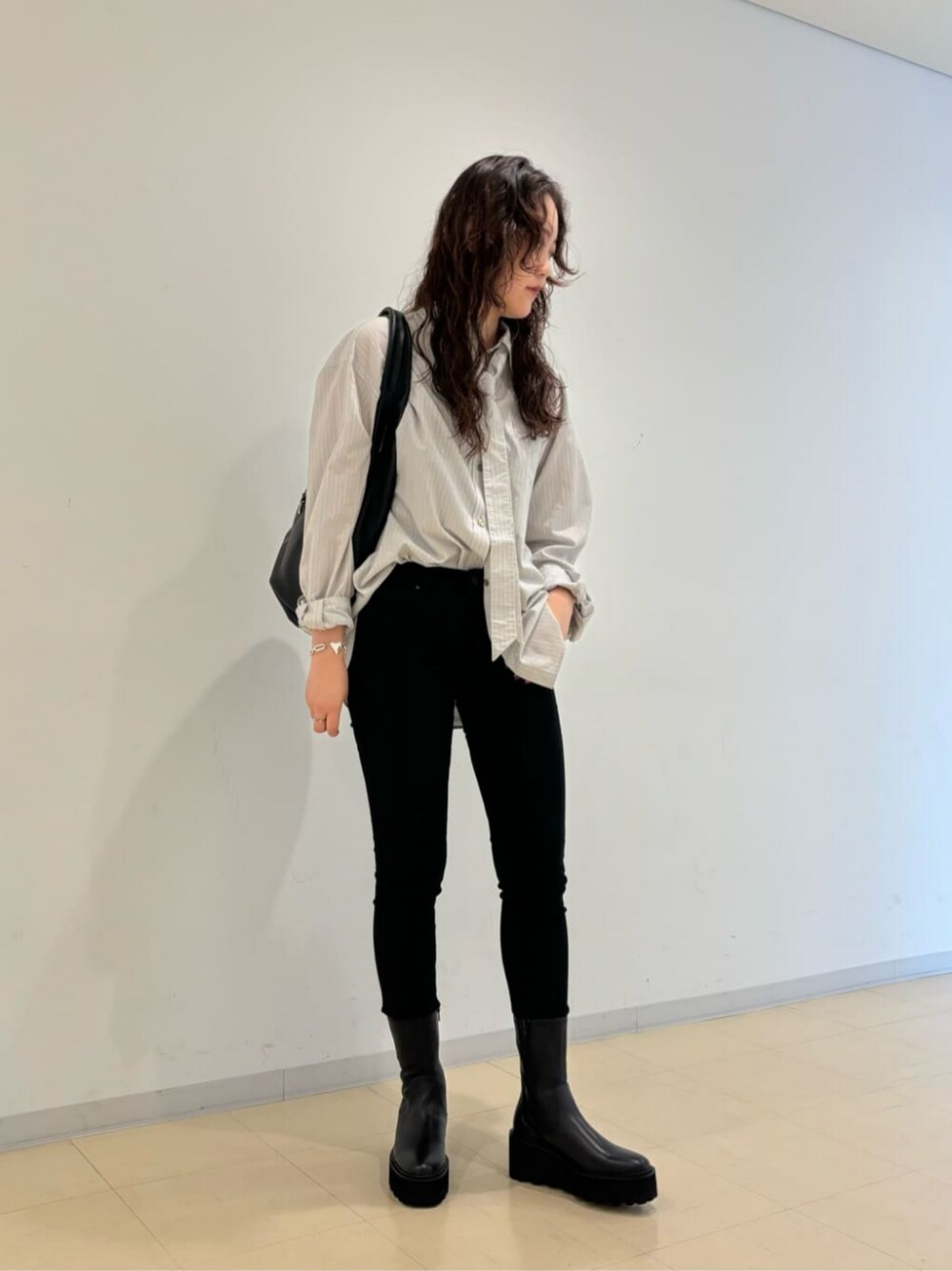 ブラック系のブーツ、ブラック系のショルダーバッグを着用したレディースの秋コーディネートの1枚目の写真