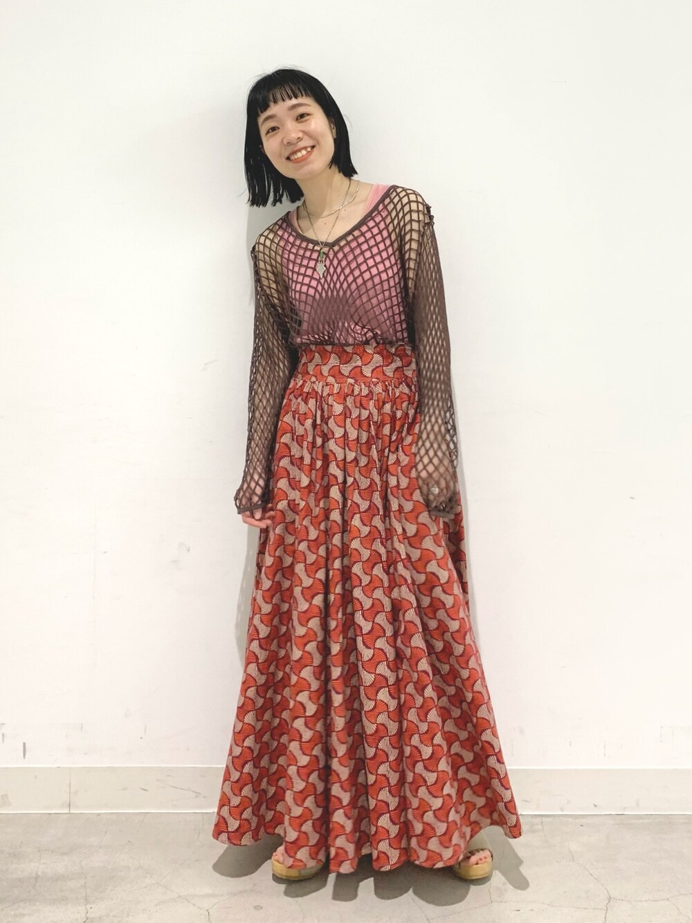 レッド系のスカート、ブラウン系のTシャツ/カットソーを着用したレディースの春コーディネートの1枚目の写真