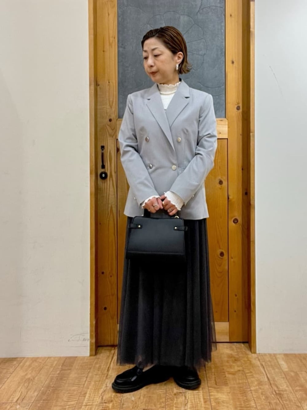 グレー系のテーラードジャケット、ホワイト系のTシャツ/カットソー、グレー系のスカートを着用したレディースの冬コーディネートの1枚目の写真