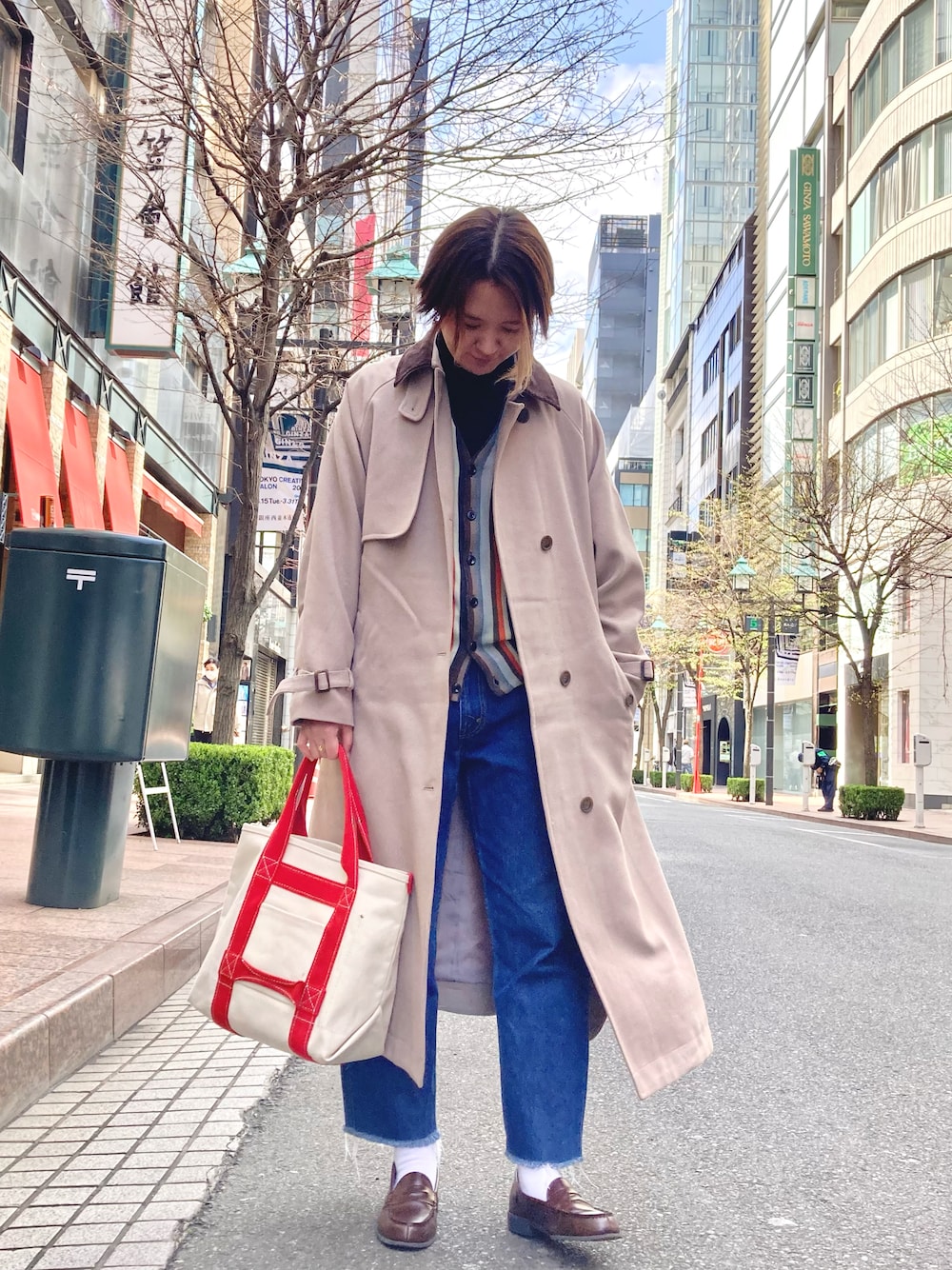 ホワイト系のトートバッグ、ブルー系のデニムパンツ、グレー系のカーディガン/ボレロを着用したレディースの春コーディネートの1枚目の写真