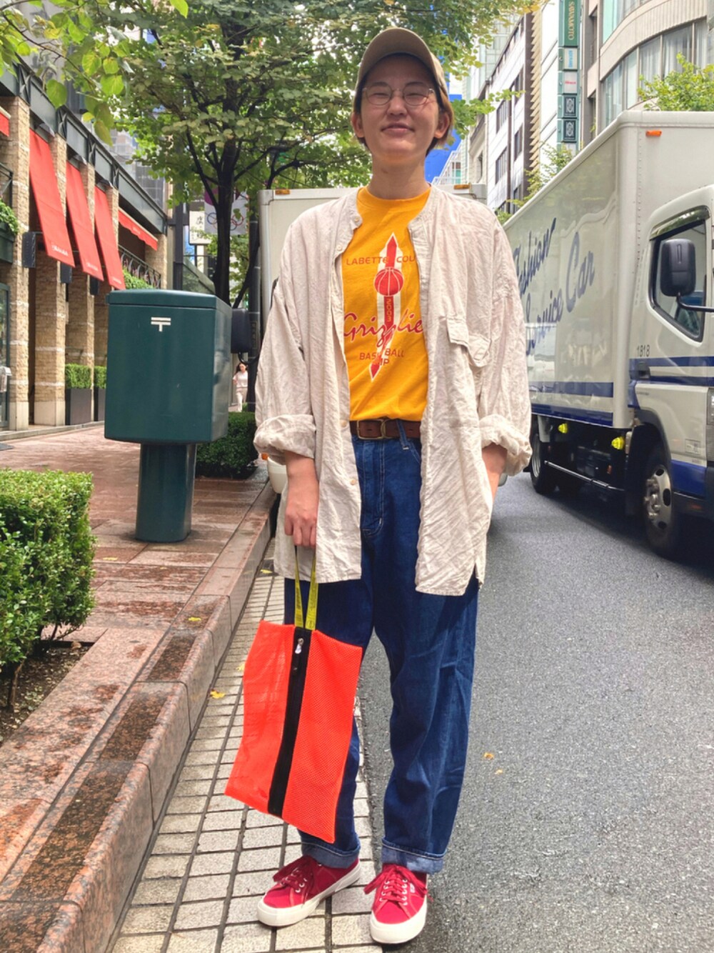 ブルー系のデニムパンツ、レッド系のスニーカー、オレンジ系のバッグを着用したレディースの夏コーディネートの1枚目の写真