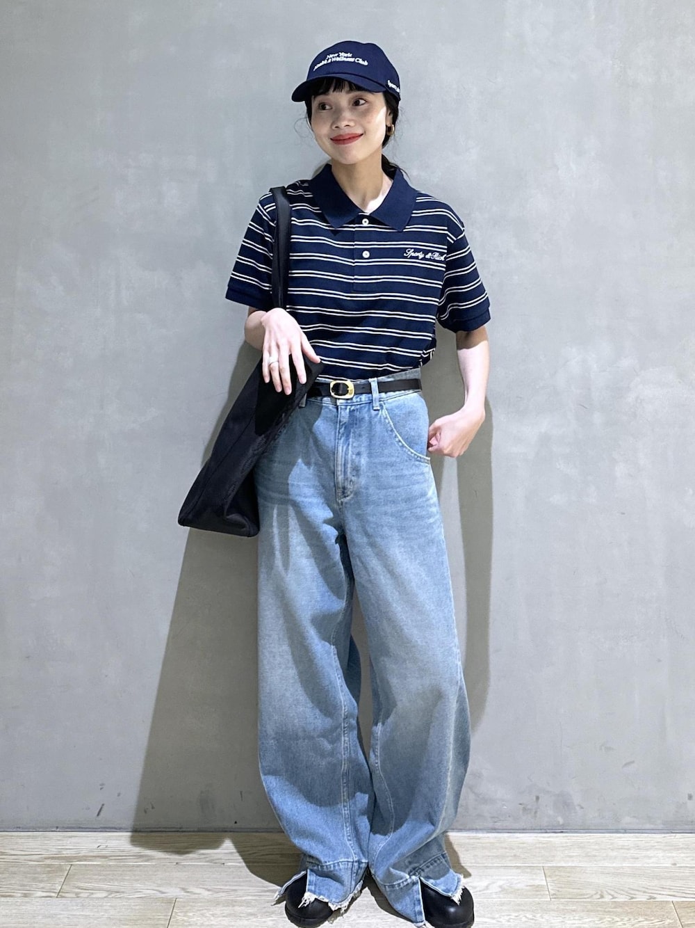 ブルー系のデニムパンツ、ブルー系のポロシャツ、ゴールド系のベルトを着用したレディースの夏コーディネートの1枚目の写真