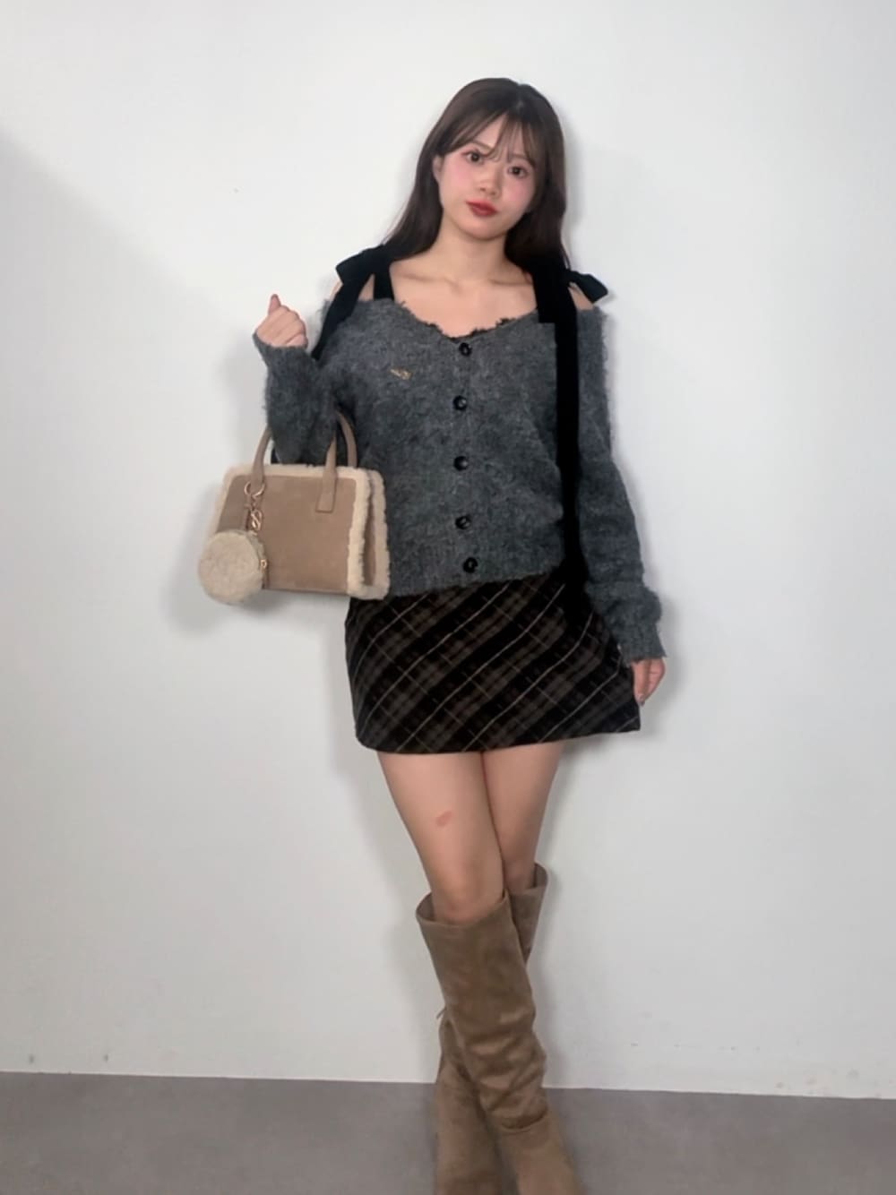 グレー系のカーディガン/ボレロ、ベージュ系のスカート、ベージュ系のブーツを着用したレディースの秋コーディネートの1枚目の写真