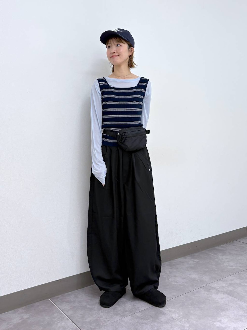 ブラック系のボディバッグ/ウエストポーチ、ブラック系のモカシン/デッキシューズ、ブラック系のスラックスを着用したレディースの春コーディネートの1枚目の写真