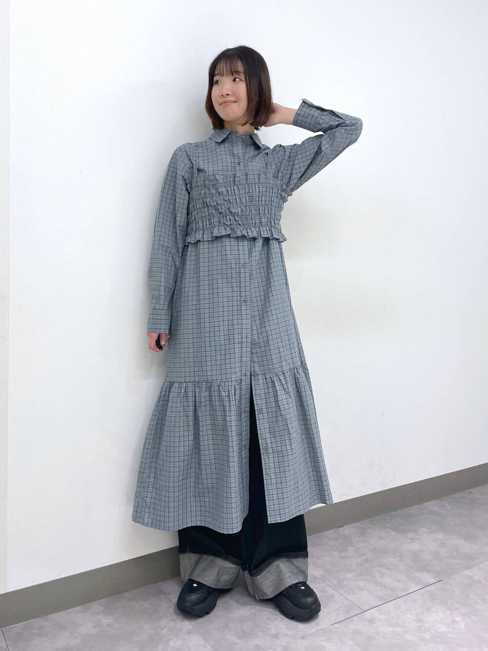 ブラック系のスニーカー、ブルー系のシャツワンピース、ブラック系のデニムパンツを着用したレディースの春コーディネートの1枚目の写真