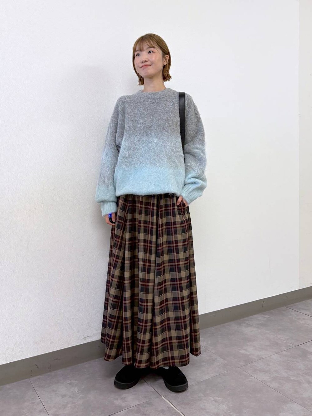 ブラック系のショルダーバッグ、レッド系のスカート、グレー系のニット/セーターを着用したレディースの秋コーディネートの1枚目の写真