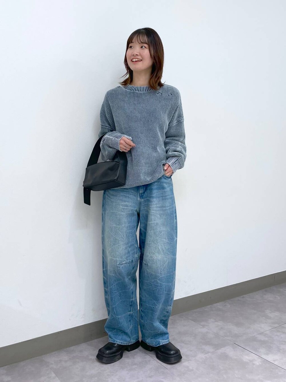 ブラック系のブーツ、ブラック系のショルダーバッグ、ブルー系のデニムパンツを着用したレディースの冬コーディネートの1枚目の写真