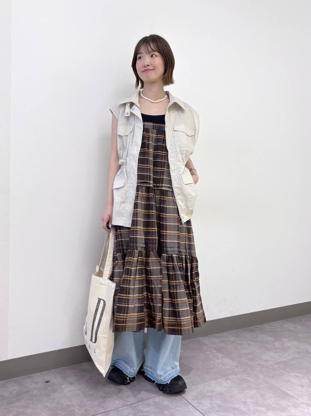 ブラック系のサンダル、ブルー系のデニムパンツ、ホワイト系のベストを着用したレディースの夏コーディネートの1枚目の写真