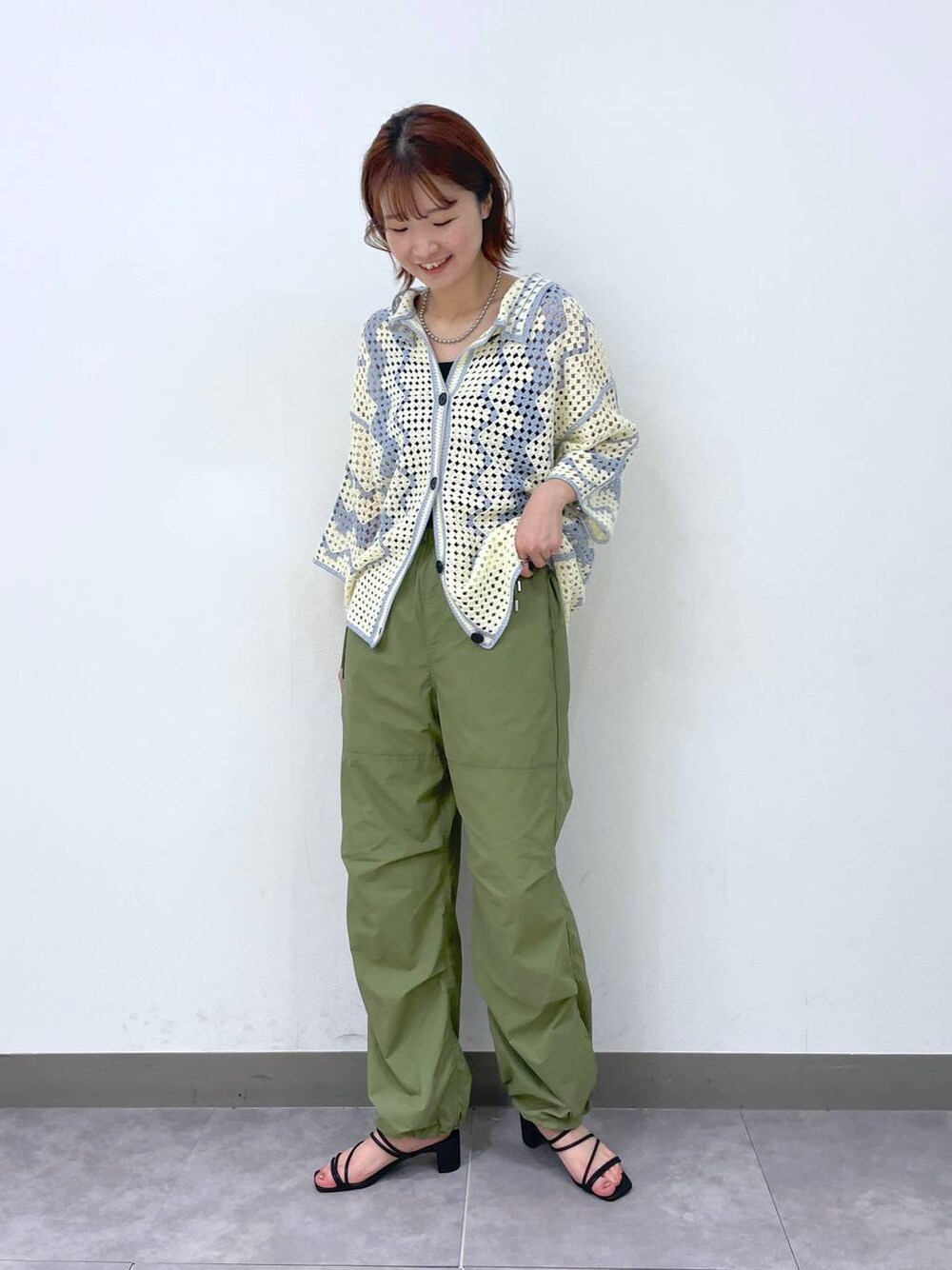 ブラック系のサンダル、ホワイト系のカーディガン/ボレロ、グリーン系のカーゴパンツを着用したレディースの夏コーディネートの1枚目の写真