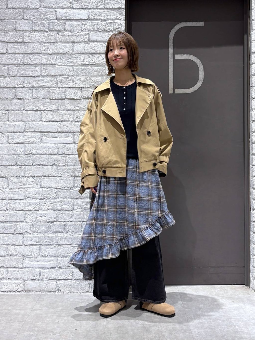 ブラック系のデニムパンツ、ベージュ系のトレンチコート、ブルー系のニット/セーターを着用したレディースの冬コーディネートの1枚目の写真