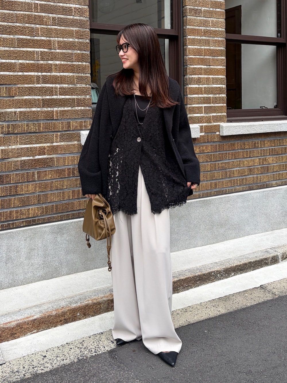 ブラック系のテーラードジャケット、ブラック系のベスト、ベージュ系のスラックスを着用したレディースの秋コーディネートの1枚目の写真