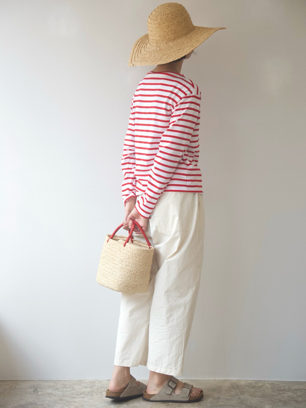 レッド系のTシャツ/カットソー、ホワイト系のパンツ、ベージュ系のかごバッグを着用したレディースの夏コーディネートの1枚目の写真