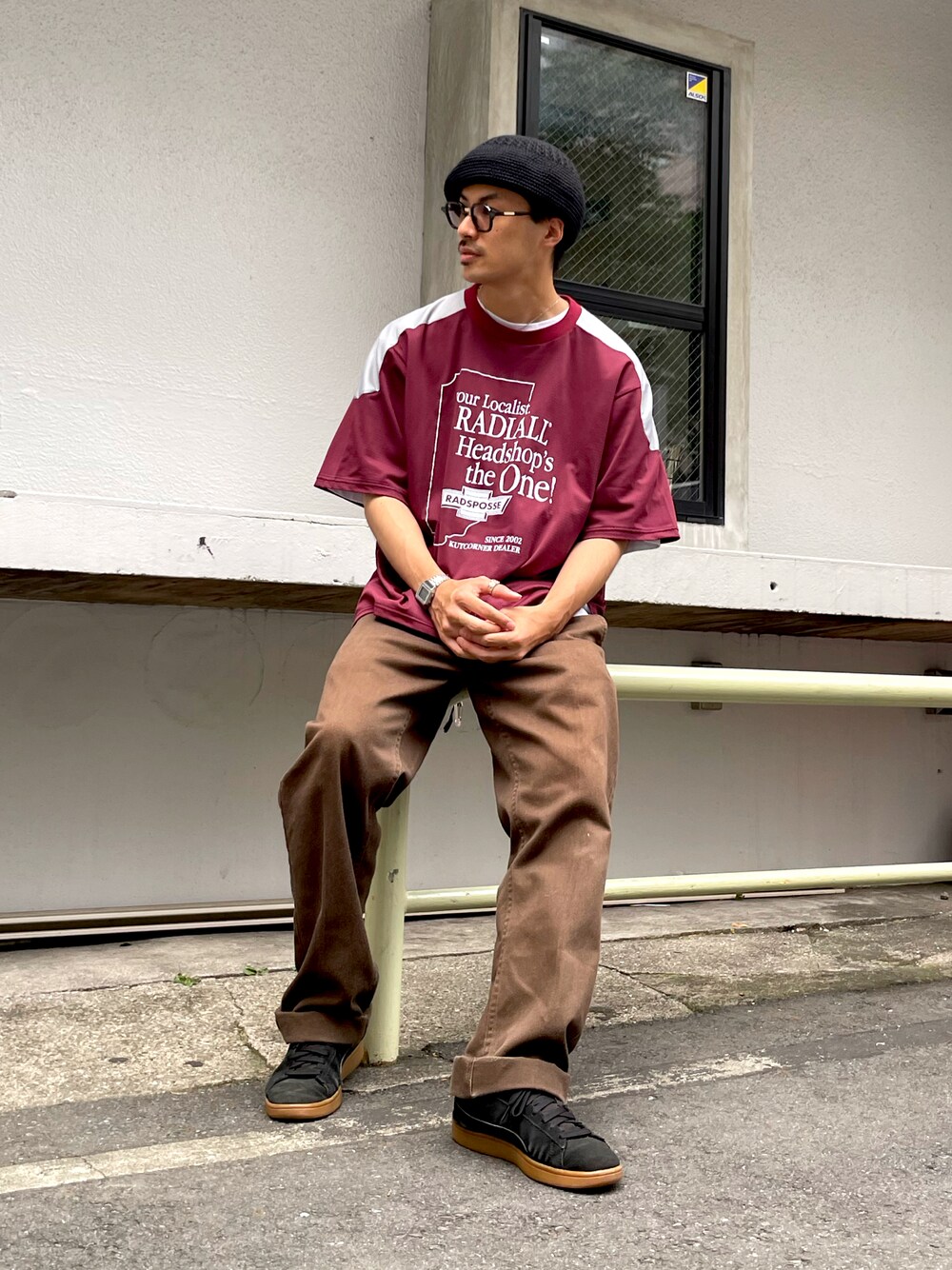 レッド系のTシャツ/カットソー、ブラウン系のチノパンツ、ブラック系のスニーカーを着用したメンズの夏コーディネートの1枚目の写真
