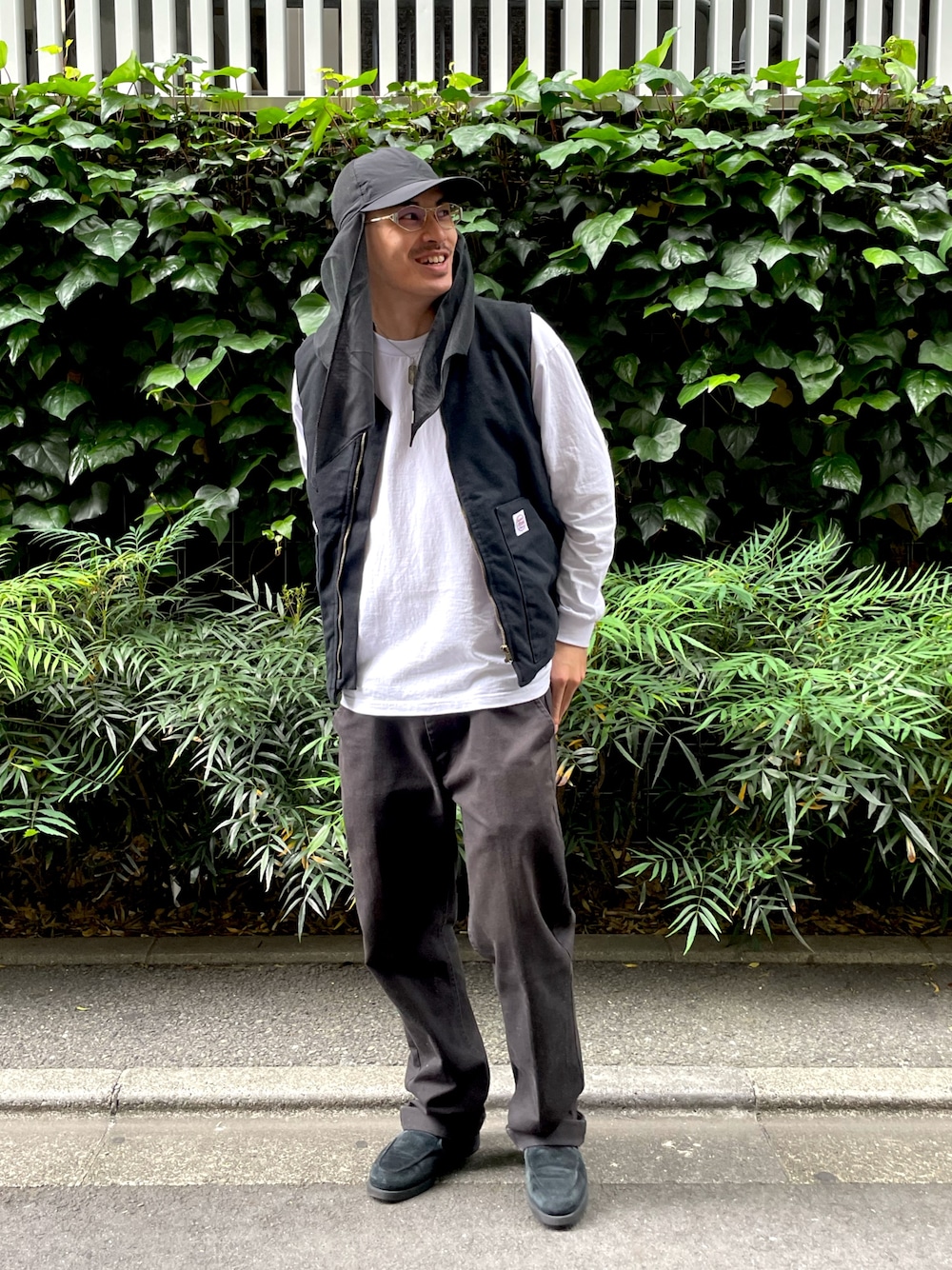 ブラック系のダウンベスト、ブラック系のチノパンツ、ブラック系のローファーを着用したメンズの夏コーディネートの1枚目の写真