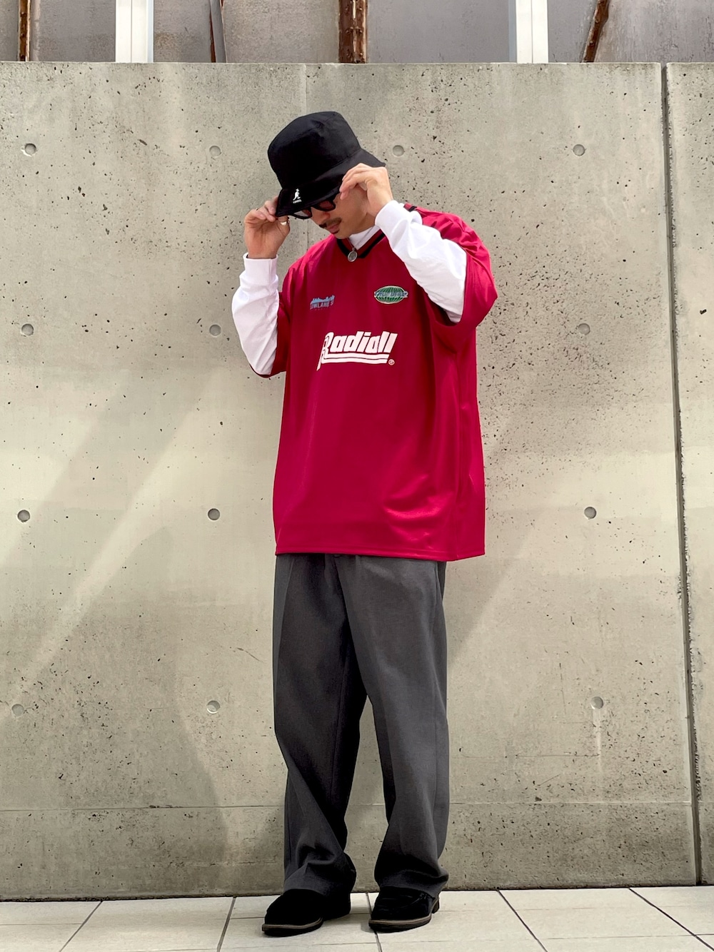 レッド系のトップス、グレー系のスラックス、ブラック系のローファーを着用したメンズの春コーディネートの1枚目の写真