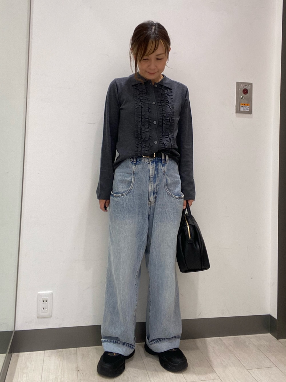 グレー系のニット/セーター、ブルー系のデニムパンツ、ブラック系のボストンバッグを着用したレディースの秋コーディネートの1枚目の写真