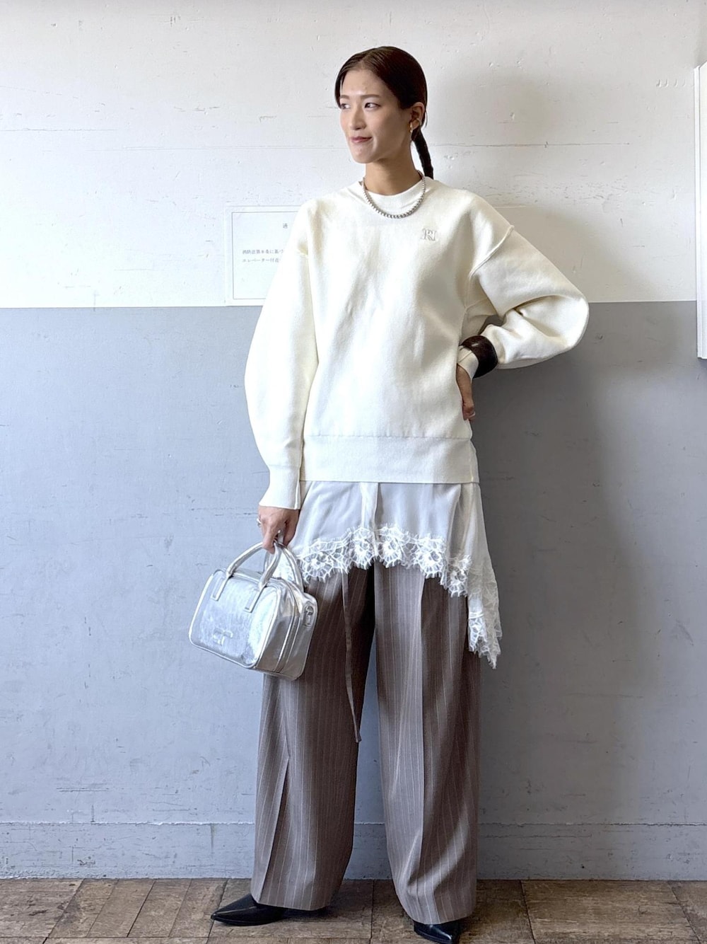シルバー系のショルダーバッグ、ホワイト系のニット/セーター、ブラック系のブーツを着用したレディースの秋コーディネートの1枚目の写真
