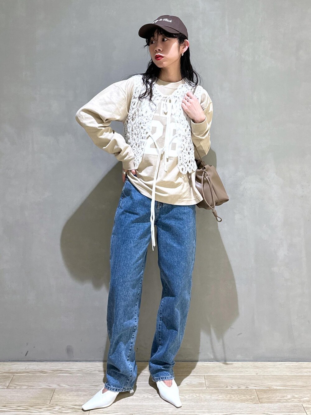 ホワイト系のベスト、ホワイト系のパンプス、ブラウン系のショルダーバッグを着用したレディースの冬コーディネートの1枚目の写真
