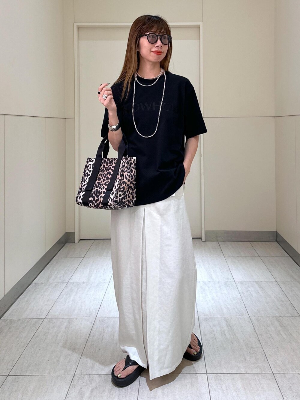 ブラウン系のショルダーバッグ、ホワイト系のスカート、ブラック系のTシャツ/カットソーを着用したレディースの夏コーディネートの1枚目の写真