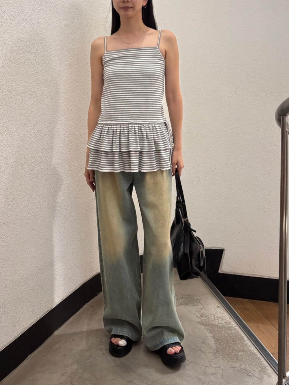 ブルー系のデニムパンツ、ブラック系のサンダル、ブラック系のハンドバッグを着用したレディースの夏コーディネートの1枚目の写真