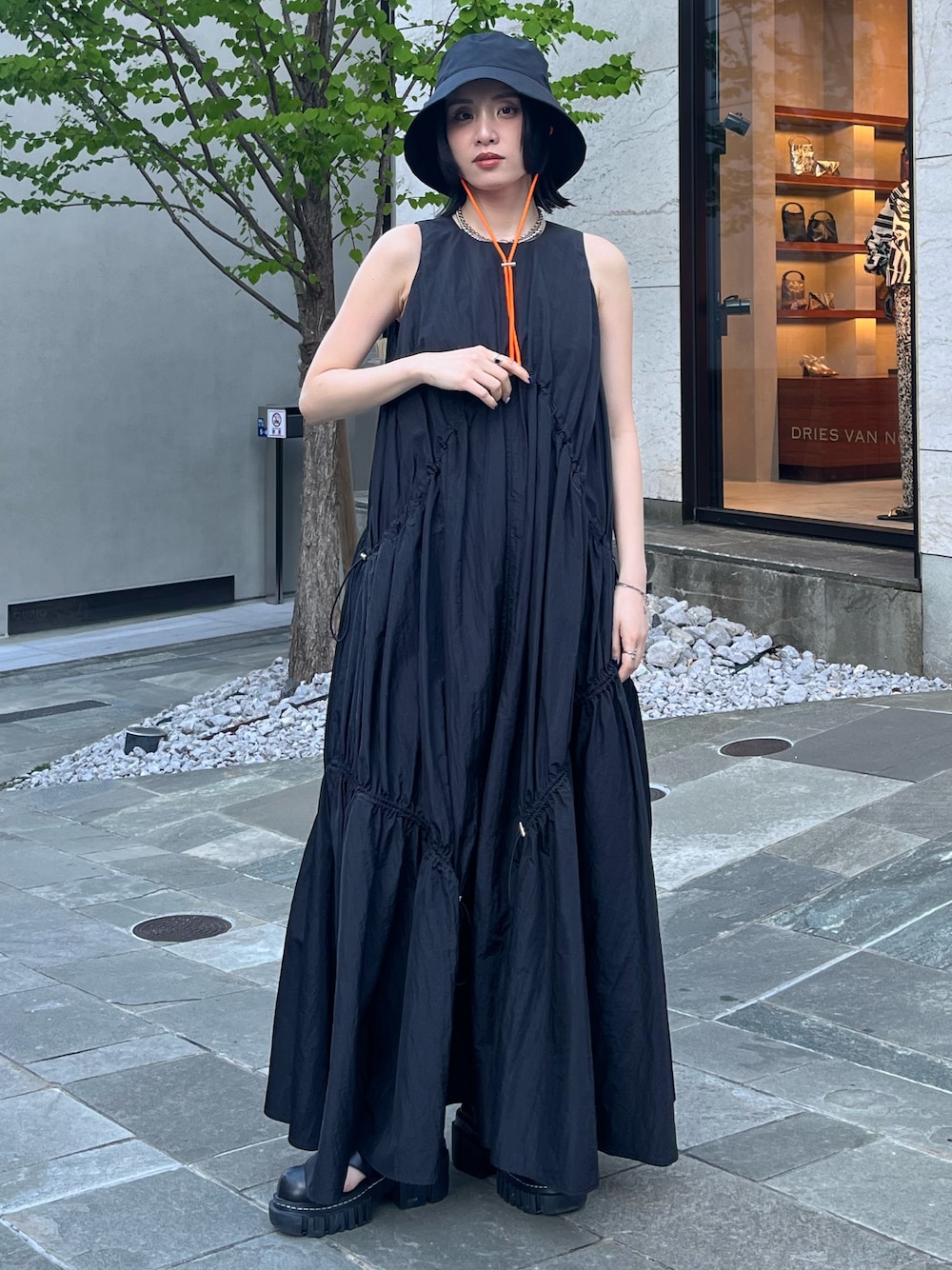 ブラック系のワンピース、ブラック系のサンダル、ブラック系のハットを着用したレディースの春コーディネートの1枚目の写真