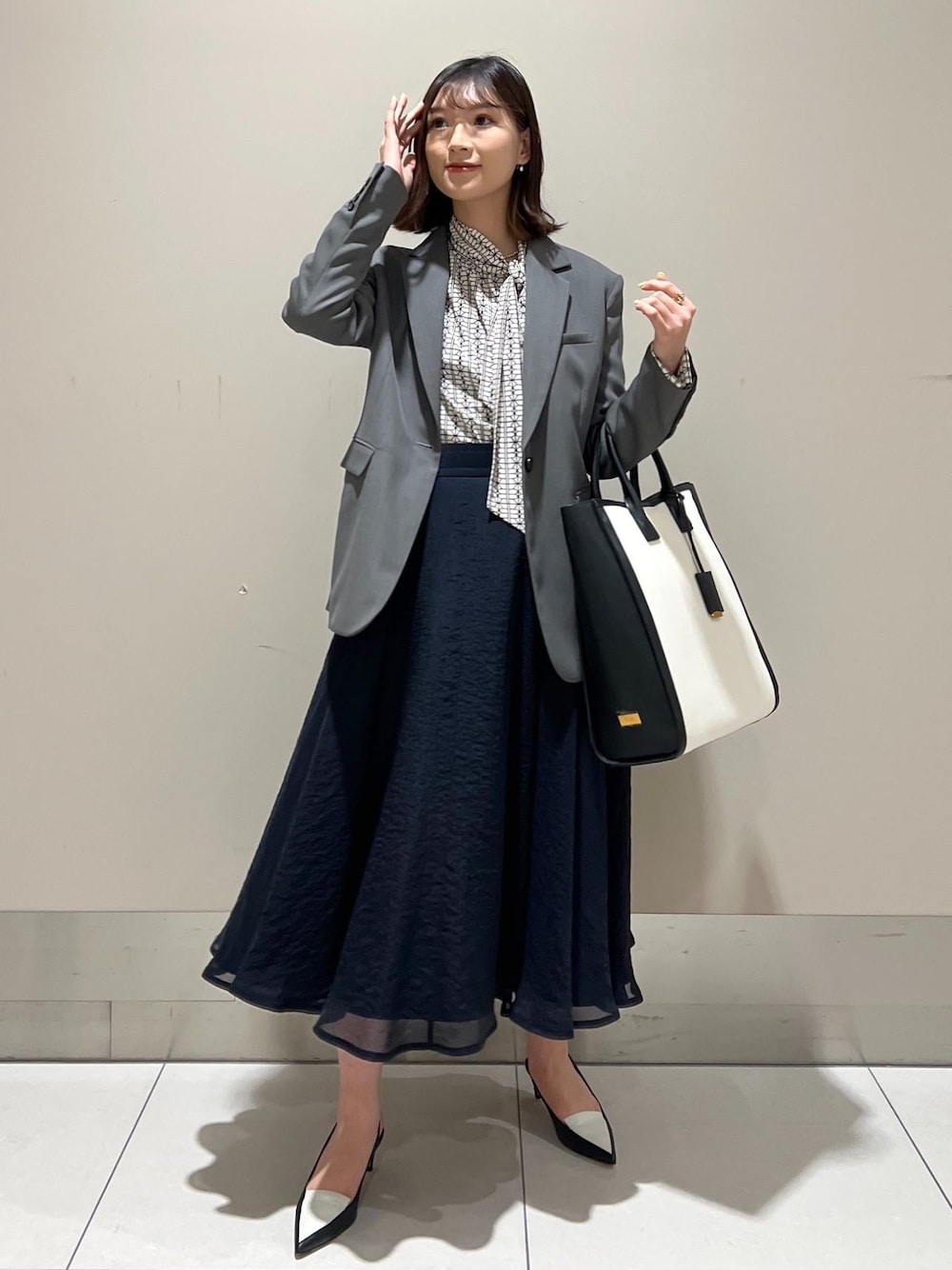 ブラック系のパンプス、ブルー系のスカート、ホワイト系のシャツ/ブラウスを着用したレディースの春コーディネートの1枚目の写真