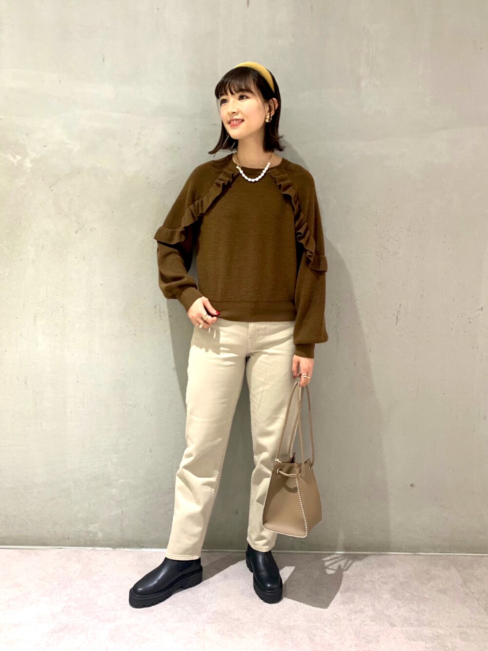 ブラウン系のワンピース、ベージュ系のデニムパンツ、ブラック系のブーツを着用したレディースの秋コーディネートの1枚目の写真