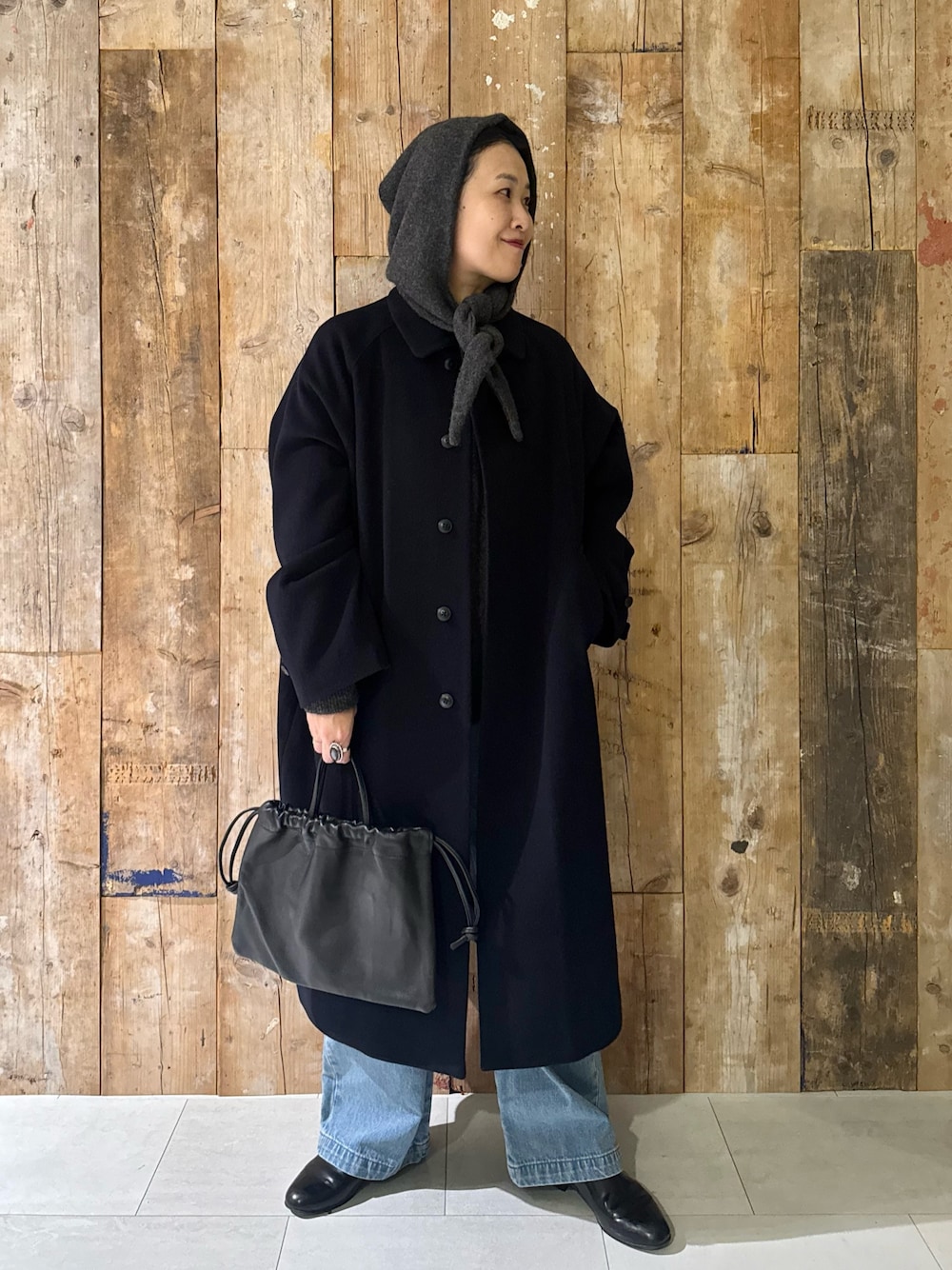 ブルー系のステンカラーコート、ブルー系のデニムパンツ、グリーン系のニット/セーターを着用したレディースの冬コーディネートの1枚目の写真