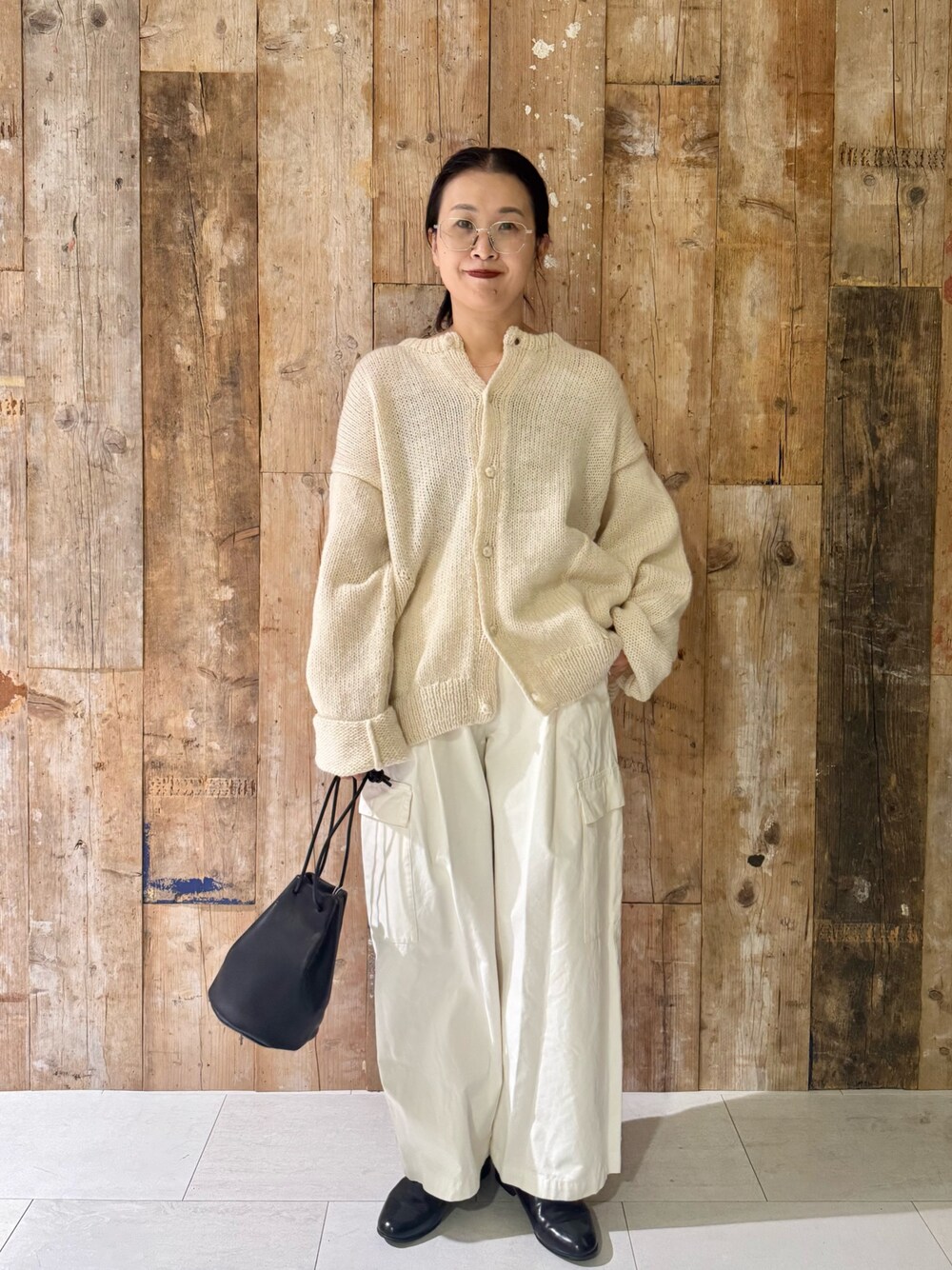 ホワイト系のその他パンツ、ホワイト系のニット/セーター、ブラック系のハンドバッグを着用したレディースの秋コーディネートの1枚目の写真