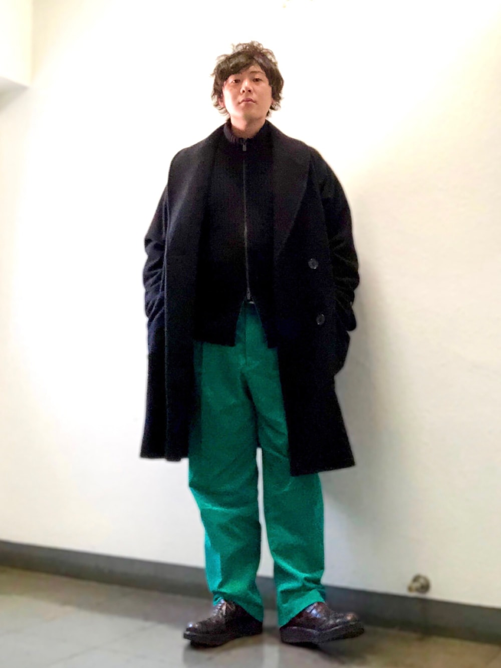 グリーン系のパンツ、ブラック系のニット/セーター、ブラック系のチェスターコートを着用したメンズの冬コーディネートの1枚目の写真