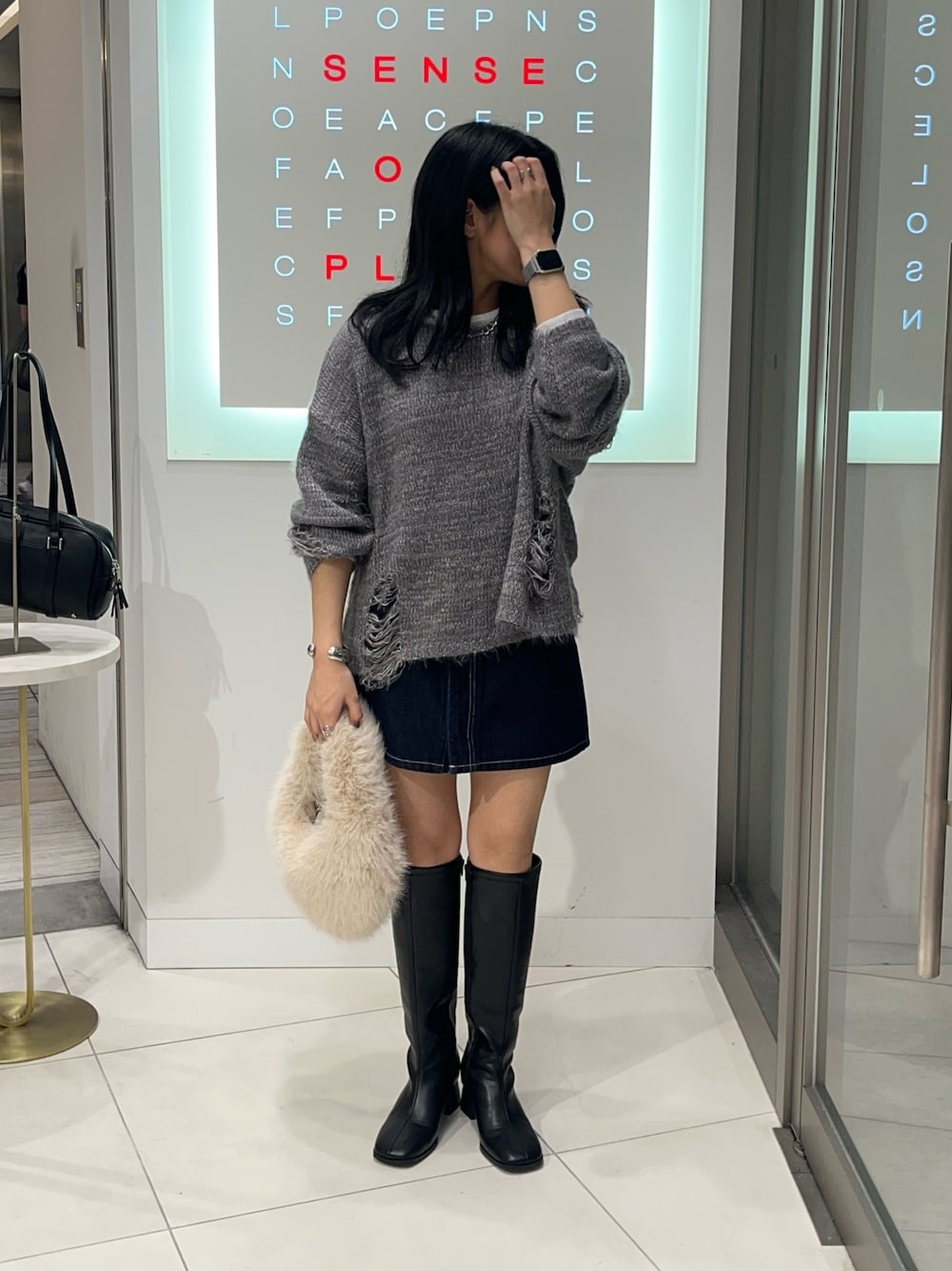 グレー系のニット/セーター、ブルー系のスカート、ホワイト系のTシャツ/カットソーを着用したレディースの秋コーディネートの1枚目の写真
